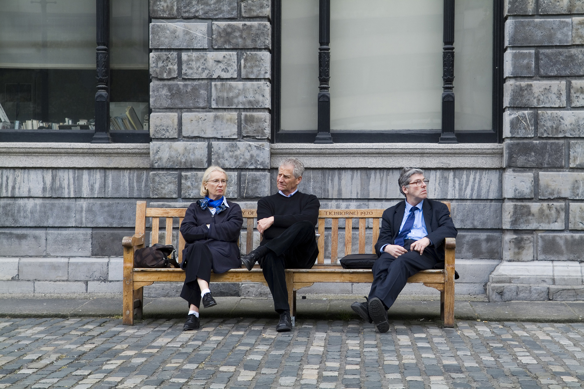 Foto di tre persone sedute su una panchina di legno.